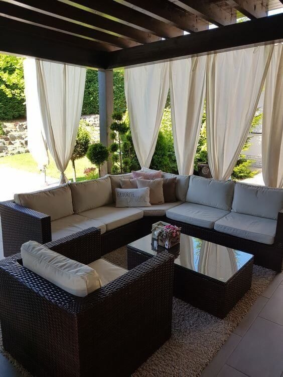Outdoor patio with rattan furniture and cream curtains on pergola