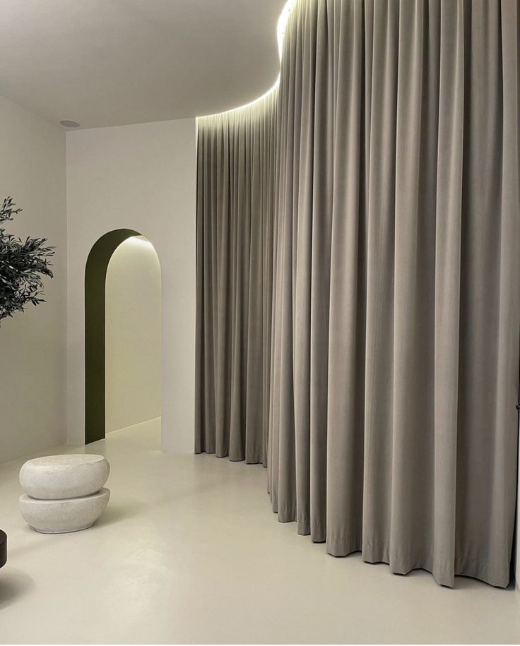 Minimalist interior with curved ceiling track curtains and archway